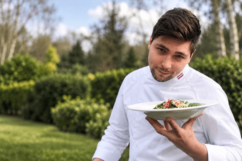 Vitalijs Solomeicuks holding a plated dish outdoors