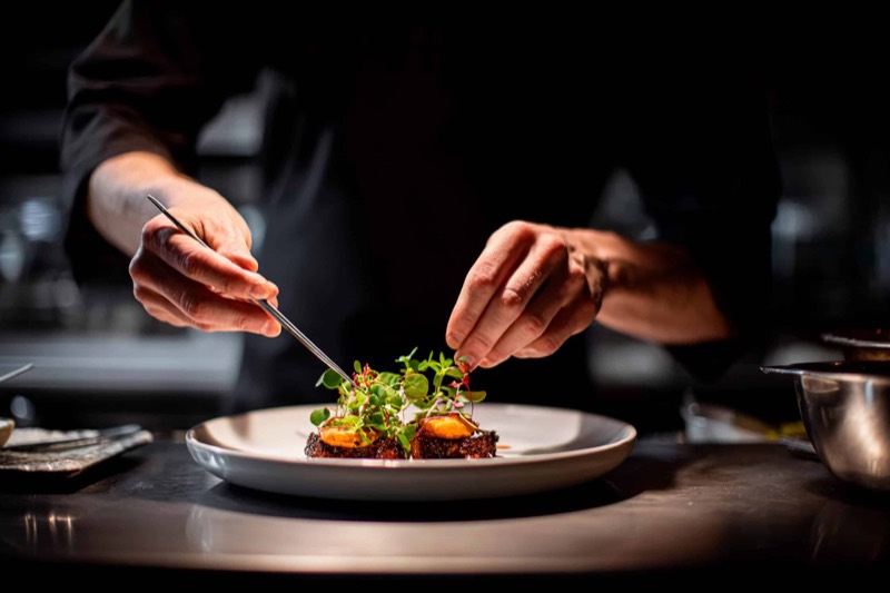 The chef plating a dish with tweezers
